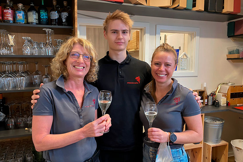 Drei Mitarbeiter lachen mit Weingläsern in der Hand