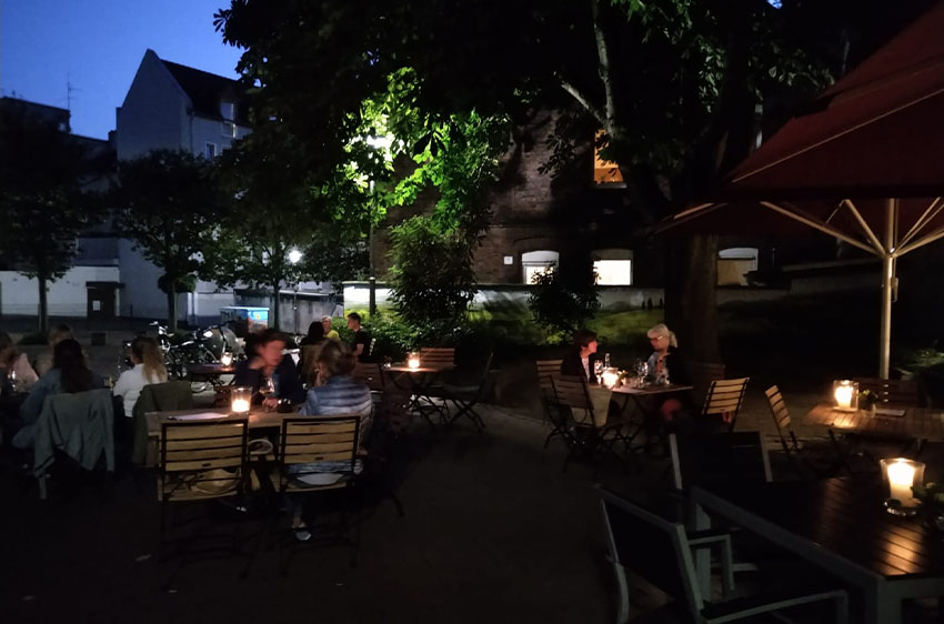 Dunkle Terrasse mit Gästen und Kerzenbeleuchtung